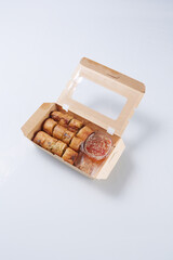 Fried Spring rolls and sweet chili dip sauce in cardboard box isolated on white background