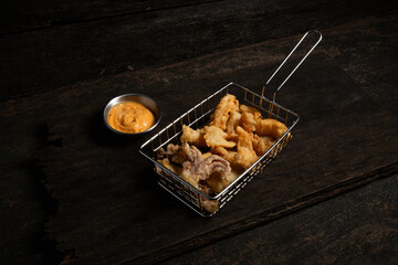 Fast food. chicken fried and squid fried in stainless steel basket on a old wooden table.
