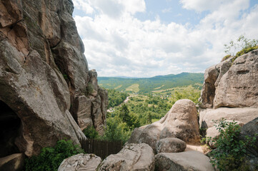 Serene Vista from Rocky Outcrop Overlooking Lush Green Valley Beneath a Dramatic Sky