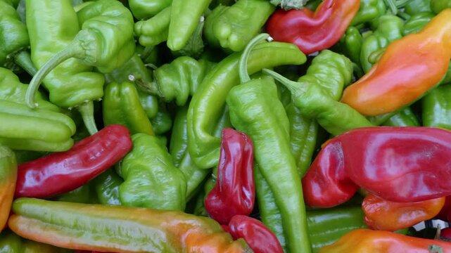 Small peppers, known as friarelli, displayed at a vibrant fruit and vegetable market stall in southern Italy.