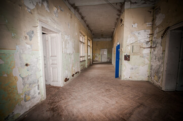 Obraz premium Haunting Corridor of a Timeworn Building with Flaking Walls and Dim Light