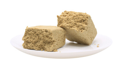 Sunflower halva in a white plate. Side view. Broken halvah pieces. Food isolated on transparent background. Isolate on png format