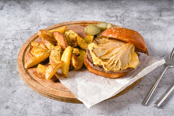 Hamburger with oyster mushrooms and cheddar cheese on a wooden cutting board