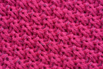 pink texture of knitted wool fabric as a background, smooth symmetrical lines of hand-knitted needlework pattern