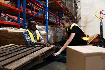 Warehouse worker african american man person has work related accident wooden Pallets falling down pressed on the legs and injured leg while working in large factory warehouse