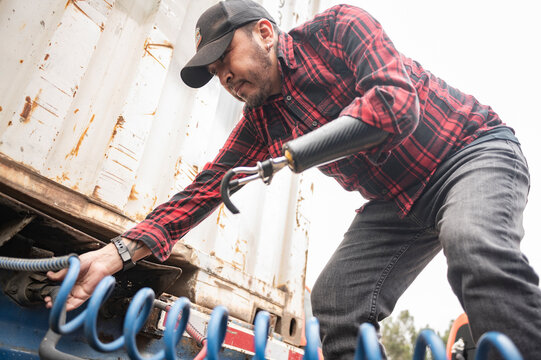 Truck driver with prosthetic arm checking the truck