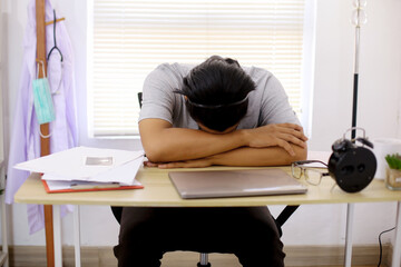 Young Asian Male Medical Student Sleeping On Desk After Tired Learning