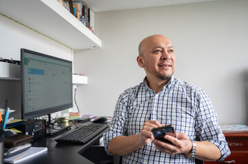 Latin man using mobile phone while working at home