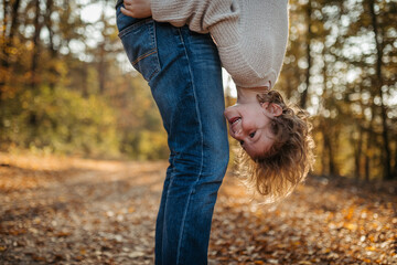 Father and girl are playful during walk in autumn forest. Dad and girl having fun outdoors.