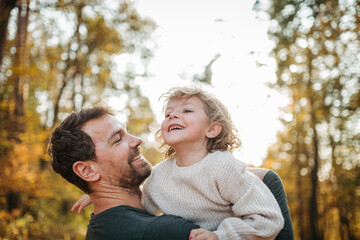 Father and girl during walk in autumn forest. Dad and girl having fun outdoors.
