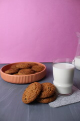 food still life oatmeal healthy cookies with milk in a glass and jug on a pink and gray background with space for text copyspace