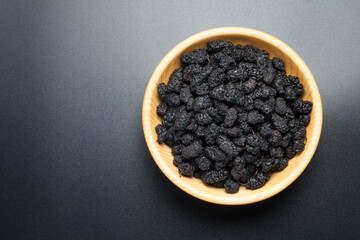 Dried black mulberries in a wooden bowl, Top view