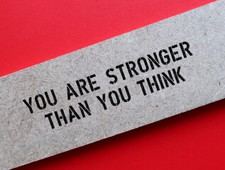 Wood on red background with message written YOU ARE STRONGER THAN YOU THINK - self talk to boost...