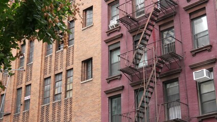 Fototapeta premium New York City classic building architecture, Manhattan, USA. Urban residential house exterior. Real estate property in United States. Typical red brick facade. Fire escape, emergency ladder exit.