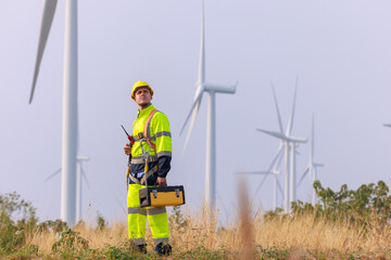 engineers wearing uniform and hardhats standing at wind turbines farm.