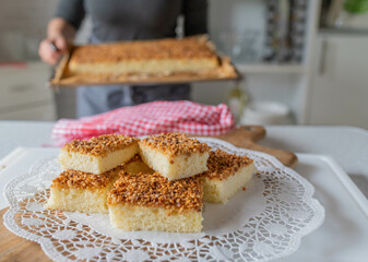 Homemade fresh baked hazelnut sheet cake served by a woman with apron in the kitchen