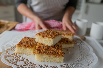 Homemade fresh baked hazelnut sheet cake served by a woman with apron in the kitchen