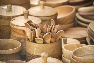 Handcrafted wooden spoons and bowls in various shapes displayed at a traditional craft market