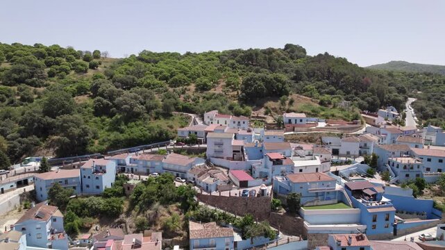 Aerial view of picturesque blue village surrounded by green hills in peaceful countryside, Juscar, Malaga, Andalucia, Spain