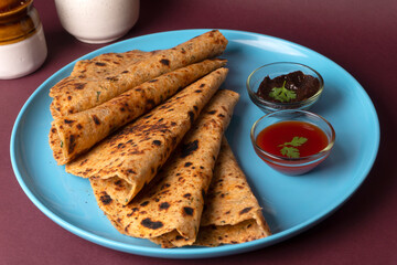 Healthy Indian Mooli or Radish paratha or stuffed flatbread with coriander and green chilli chutney on wooden background