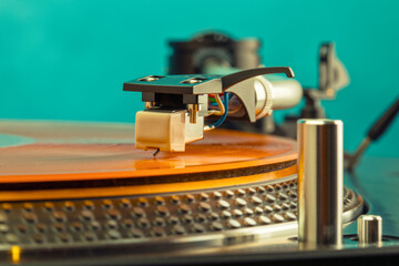 Closeup of turntable needle on orange vinyl record