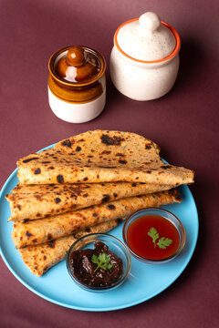 Healthy Indian Mooli or Radish paratha or stuffed flatbread with coriander and green chilli chutney on wooden background