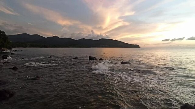 sunset sky with pink clouds and the sea waves againt the coast in Sainte Rose, in front of cluny beach. Relaxing landscape video