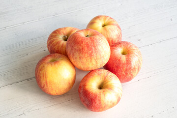 Six red apples on a white wooden board table