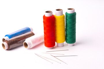 Colorful sewing thread set and needles isolated on background.
