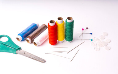 Colorful sewing thread set and needles isolated on background.