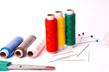 Colorful sewing thread set and needles isolated on background.