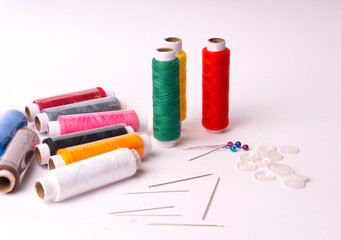 Colorful sewing thread set and needles isolated on background.