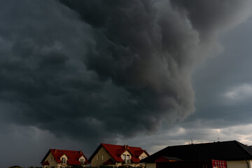 Dark storm clouds forming over suburban houses in the countryside.