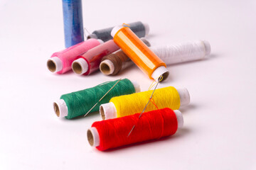 Colorful sewing thread set and needles isolated on background.