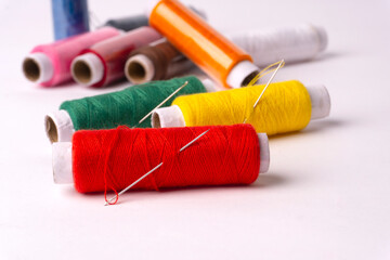 Colorful sewing thread set and needles isolated on background.