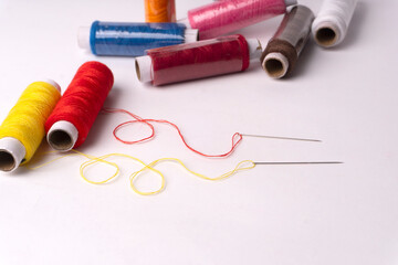 Colorful sewing thread set and needles isolated on background.