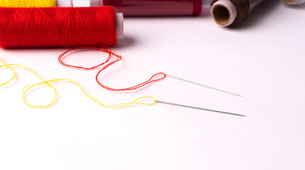 Colorful sewing thread set and needles isolated on background.