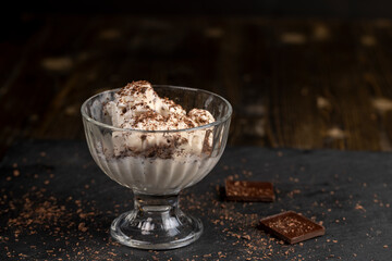 white creamy ice cream with pieces and crumbs of chocolate in a glass bowl