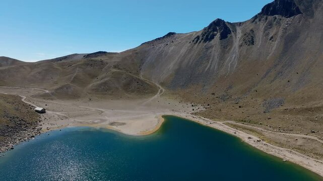 Drone flight at Nevado de Toluca reveals high-altitude peaks and the glacial waters of Laguna del Sol, Mexico. Pan left, descending view
