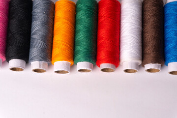 Colorful sewing thread set and needles isolated on background.