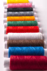Colorful sewing thread set and needles isolated on background.