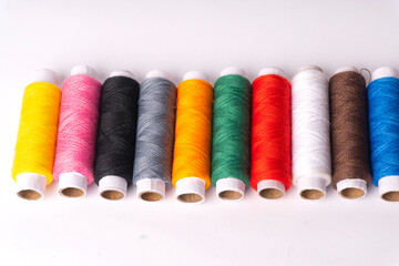 Colorful sewing thread set and needles isolated on background.