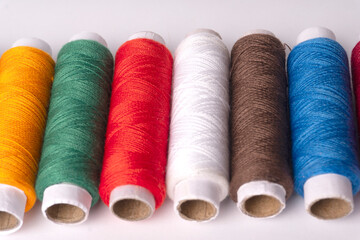 Colorful sewing thread set and needles isolated on background.