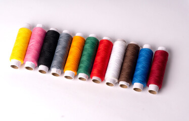 Colorful sewing thread set and needles isolated on background.