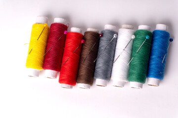 Colorful sewing thread set and needles isolated on background.