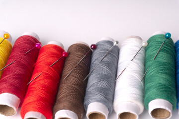 Colorful sewing thread set and needles isolated on background.