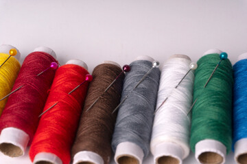 Colorful sewing thread set and needles isolated on background.