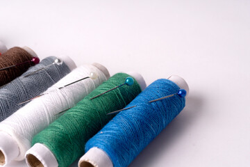 Colorful sewing thread set and needles isolated on background.