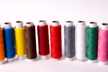 Colorful sewing thread set and needles isolated on background.