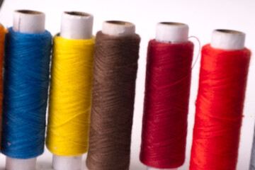 Colorful sewing thread set and needles isolated on background.